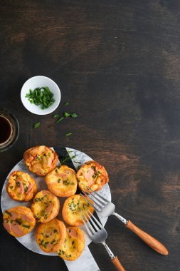 Yeşil soğanlı, pastırmalı, peynirli ve domatesli nefis yumurtalı kekler ahşap ahşap arka planda. Sağlıklı yüksek protein ve düşük karbonhidratlı kahvaltı. Ev yapımı yemek..