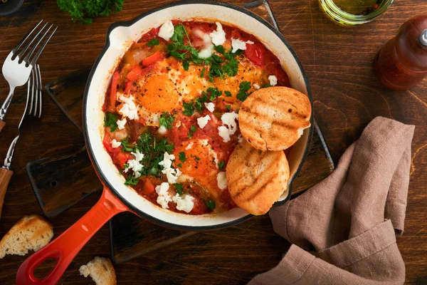 Shakshuka 自制煎蛋用西红柿 橄榄油 洋葱和大蒜在旧的木制底铁锅中腌制而成 以色列的传统美食 深夜早餐的概念 图库照片