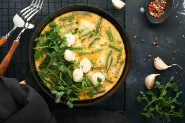 Frittata. Ispanaklı ve yeşil fasulyeli omlet. Siyah tavada sağlıklı yiyecekler. Sağlıklı kahvaltı çok lezzetli. En üstteki düz yerde. Boşluğu kopyala.