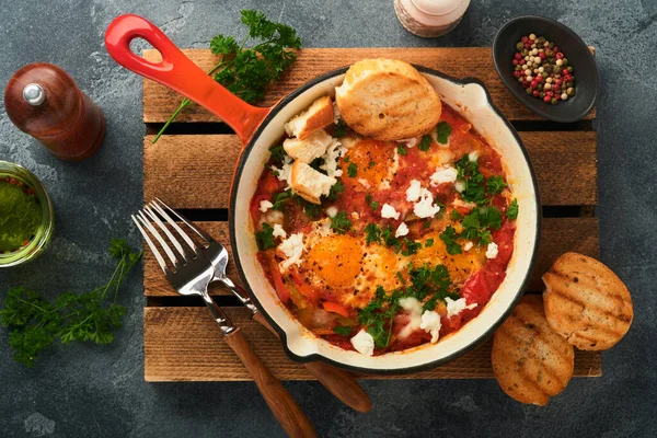 夏奇舒卡自制煎蛋 用西红柿 橄榄油 洋葱和大蒜在铁锅中 在陈腐的灰色板岩背景下腌制而成 以色列的传统美食 深夜早餐的概念 免版税图库图片