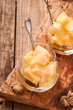 Kavun. Eski ahşap arka planda cam içinde meyve tatlısı yapmak için taze kavun parçaları. Model yap. Üst görünüm.