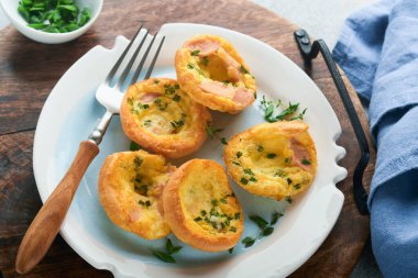 Beyaz tabakta yeşil soğanlı yumurta kekleri, pastırma, peynir ve domates. Sağlıklı yüksek protein ve düşük karbonhidratlı kahvaltı, yemeye hazır..