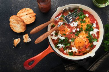 Shakshuka. Ev yapımı sahanda yumurta ve demir tavada sebzeler. Eski koyu levha, taş ya da beton arka plan. Geleneksel İsrail mutfağı. Geç kahvaltı konsepti. Arap mutfağı. Üst görünüm.