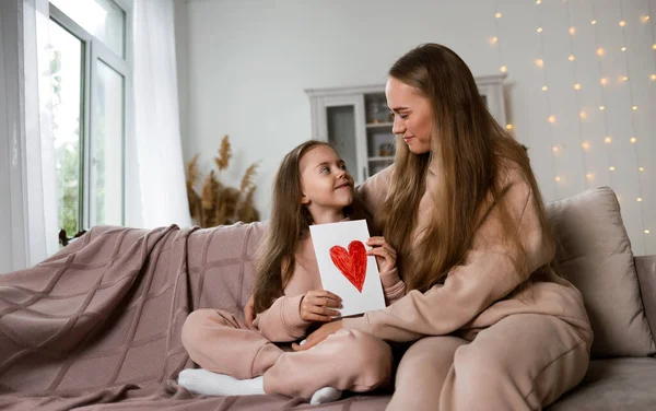 Sweatshirt 'lü güzel anne-kız kanepede oturup anneler gününü kutluyorlar.