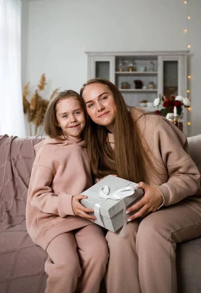 Güzel anne ve kız kanepede oturmuş hediye kutusuyla kameraya bakıyorlardı.
