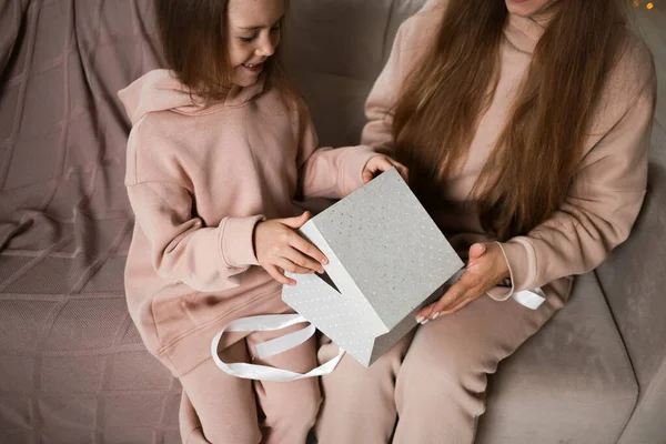 Bir anne ve kızın hediye kutusuyla kanepede oturması ve onu açması.