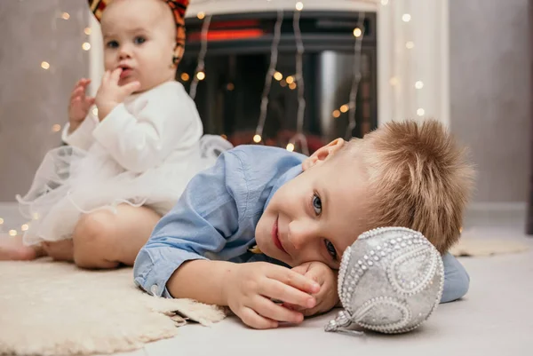 小さな男の子が新年の舞踏会の横にある毛皮の絨毯の上に横たわっている — ストック写真