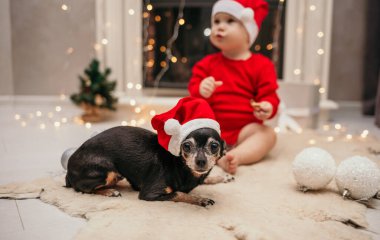 Kırmızı Noel şapkalı bir cüce şöminenin yanında bir çocukla oturuyor.