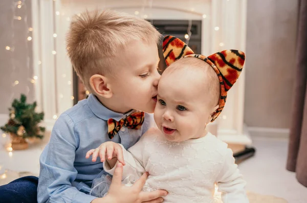 弟がお正月の暖炉のそばの赤ん坊の妹とキスして — ストック写真
