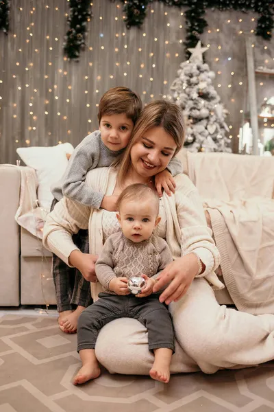 幸せな母親と息子たちは新年の背景にソファの近くの部屋に座っています — ストック写真