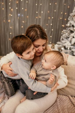 Mutlu anne kanepede oturuyor ve yeni yılda oğullarına sarılıyor.