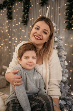 Anne, Noel ağacının yanındaki odada oğluna sarılıyor.