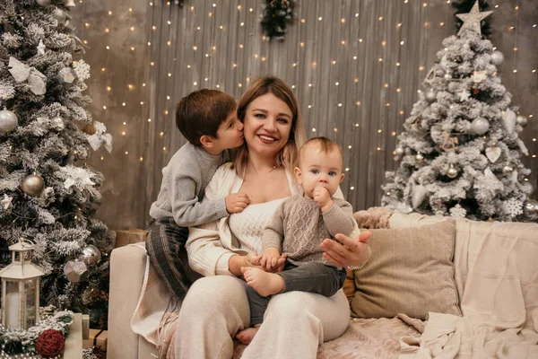 息子と幸せな母親が部屋のクリスマスツリーの近くのソファに座っている — ストック写真