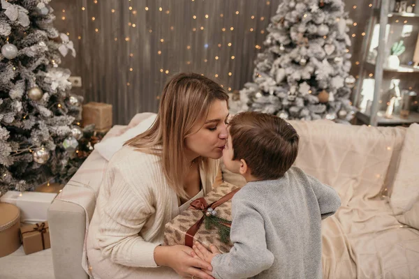 ママはソファに座ってクリスマスツリーの近くの部屋で息子とキスしてる — ストック写真