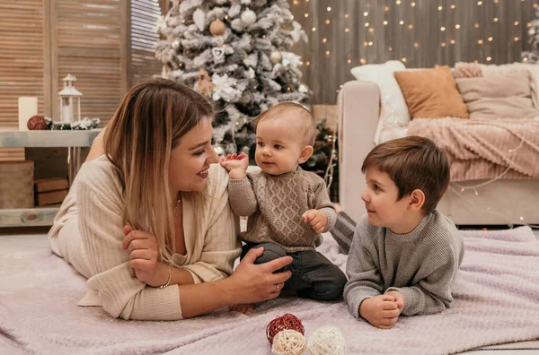 幸せな母親と息子はクリスマスツリーの近くの部屋の毛布の上に横たわっています — ストック写真