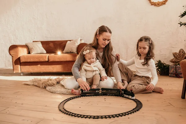 母親と娘は部屋のカーペットの上に座って電車で鉄道と遊んでいます — ストック写真