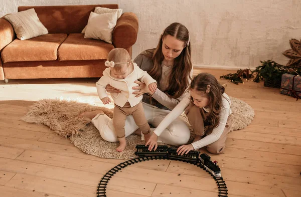 幸せなお母さんはおもちゃの鉄道で部屋の床で遊んでいます — ストック写真
