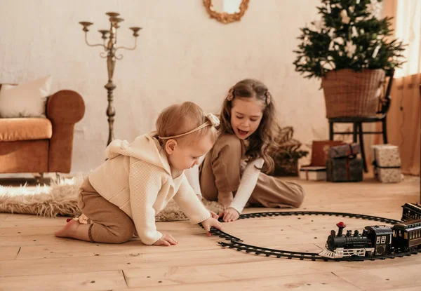 赤ん坊の女の子が電車や妹と電車で床で遊んでいます — ストック写真