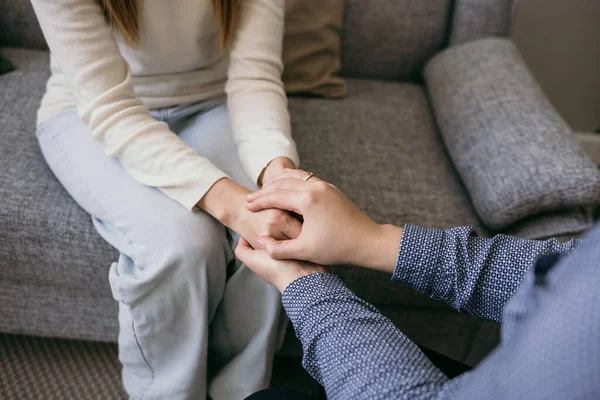 Hastanın ellerine sarılan bir kadın doktorun yakın çekimi. Bir destek jesti. Bir kadına psikolojik yardım