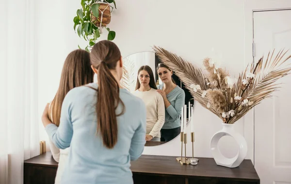 İki esmer kadın ayakta dikilip aynada kendilerine bakıyorlar. Arkadaş desteği