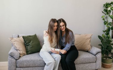 Kadınlara psikolojik yardım. Aile içi şiddet. İki kadın kanepede oturuyor ve sarılıyorlar. Destekleyici sarılmalar.