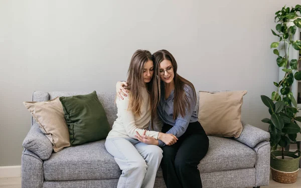 Kadınlara psikolojik yardım. Aile içi şiddet. İki kadın kanepede oturuyor ve sarılıyorlar. Destekleyici sarılmalar.