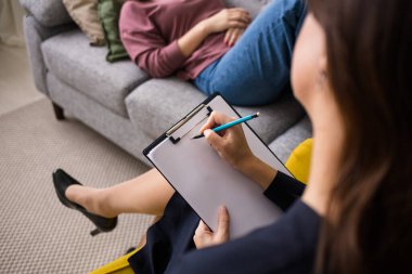 Beyaz kağıda kalemle yazan bir kadının yakın çekimi. Veri kaydı