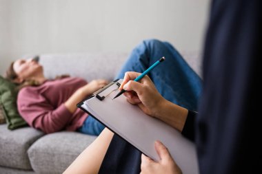 Beyaz kağıda kalemle yazan bir kadının yakın çekimi. Veri kaydı