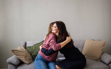 Kadınlara psikolojik yardım. İki kadın kanepede oturuyor ve sarılıyorlar. Destekleyici sarılmalar.