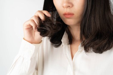 Young woman worried about dry hair, damaged hair and split ends. Hair problems and hair care concept.