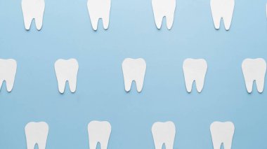 Kağıttan yapılmış beyaz dişlerin üst görüntüsü açık mavi sırt grond üzerinde. Diş konsepti. Asgari.