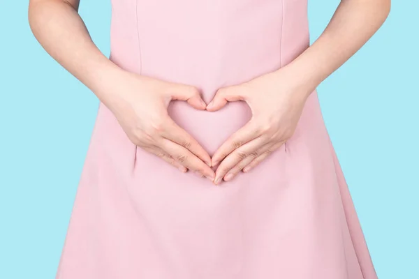 Close up of healthy woman hand made heart shape on her stomach. Concept of good digestive, healthy gut, probiotics, slim fit, gynecology and woman health care.