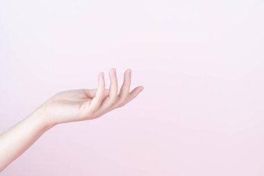 Kadın eli, pembe arka planda ürün için açık avuç içini fotokopi aletiyle sunar veya gösterir. Kapat..