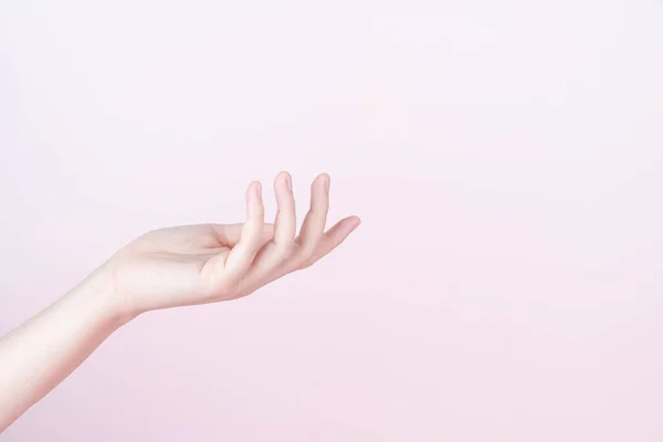 Woman hand presenting or showing open hand palm with copy space for product over pink background. Close up.