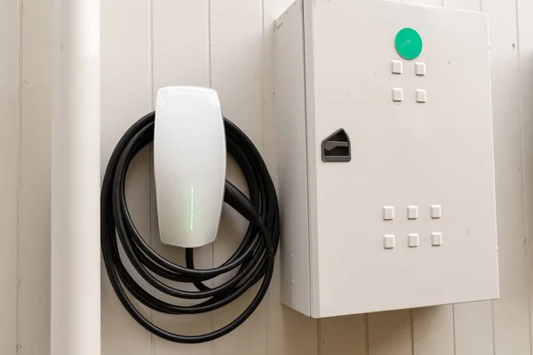 Yanı başında sigorta kutusu olan bir evin duvarında elektrikli araba şarjı var.