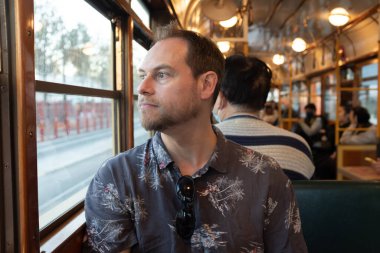 Ünlü tarihi Melbourne W sınıfı tramvayda oturan bir adam pencereden dışarı bakıyor.