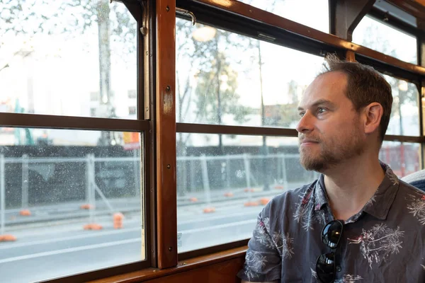 Ünlü tarihi Melbourne W sınıfı tramvayda oturan bir adam pencereden dışarı bakıyor.