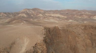 A man is walking at the end of a mountain in a desert landscape.