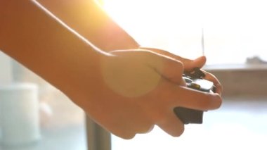 Playing Video games at Home. Close-up Hand and game console Controller, Sunbeams in the background.