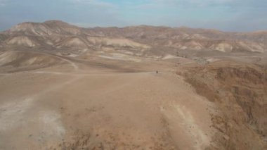 A man is walking at the end of a mountain in a desert landscape.