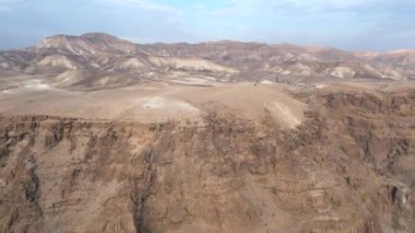 A man is walking at the end of a mountain in a desert landscape.