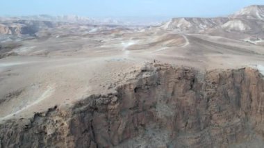 A man is walking at the end of a mountain in a desert landscape.