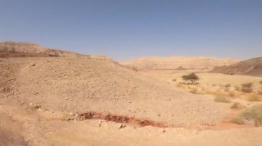 Dağlar ve mavi gökyüzüyle çölde bir kır yolunda giden araba..