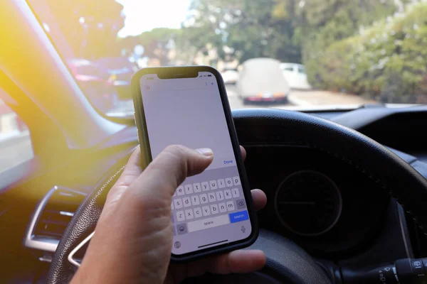 Writing and typing message with cellphone in vehicle. Texting while driving a car.
