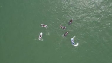 Açık yeşil Pasifik okyanus sularında birkaç jet ski 'nin üstünde tepeden aşağı manzara.