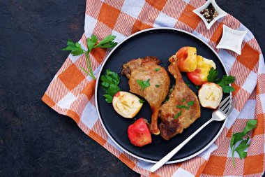 Koyu beton arka planda siyah bir tabakta elmalı fırında ördek bacağı. Noel ve Yeni Yıl konsepti. Ördek tarifleri. Şükran Günü. Üst görünüm.