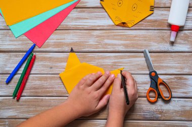 Oğlan, origami kaplanını, ahşap bir arka planda, turuncu kağıttan adım adım katlıyor. Çin takviminde 2022 yılının sembolü. Çocukların yaratıcılığı