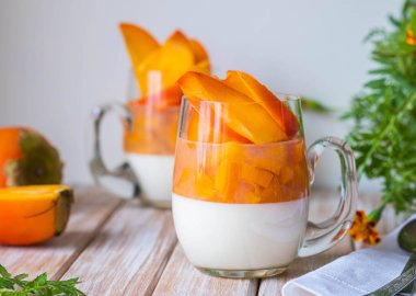 Tatlı, panna cotta ya da ekşi kremalı jöle ve ahşap arka planda cam bardaklarda hurma. Panna cotta tarifleri. İtalyan yemeği..