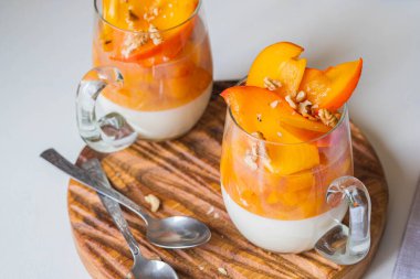 Tatlı, panna cotta ya da ekşi kremalı jöle. Hafif arka planda tahta bir tahtada cam bardakta hurma. Panna cotta tarifleri. İtalyan yemeği..