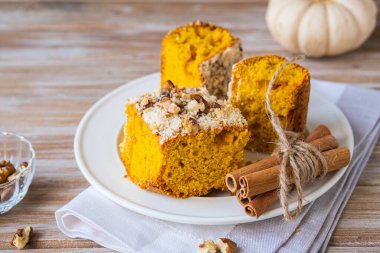Dilimlenmiş balkabağı ya da ahşap bir zeminde beyaz bir tabakta ceviz ve streusel ile havuçlu kek. Balkabağı pişirme tarifleri. Şükran Günü